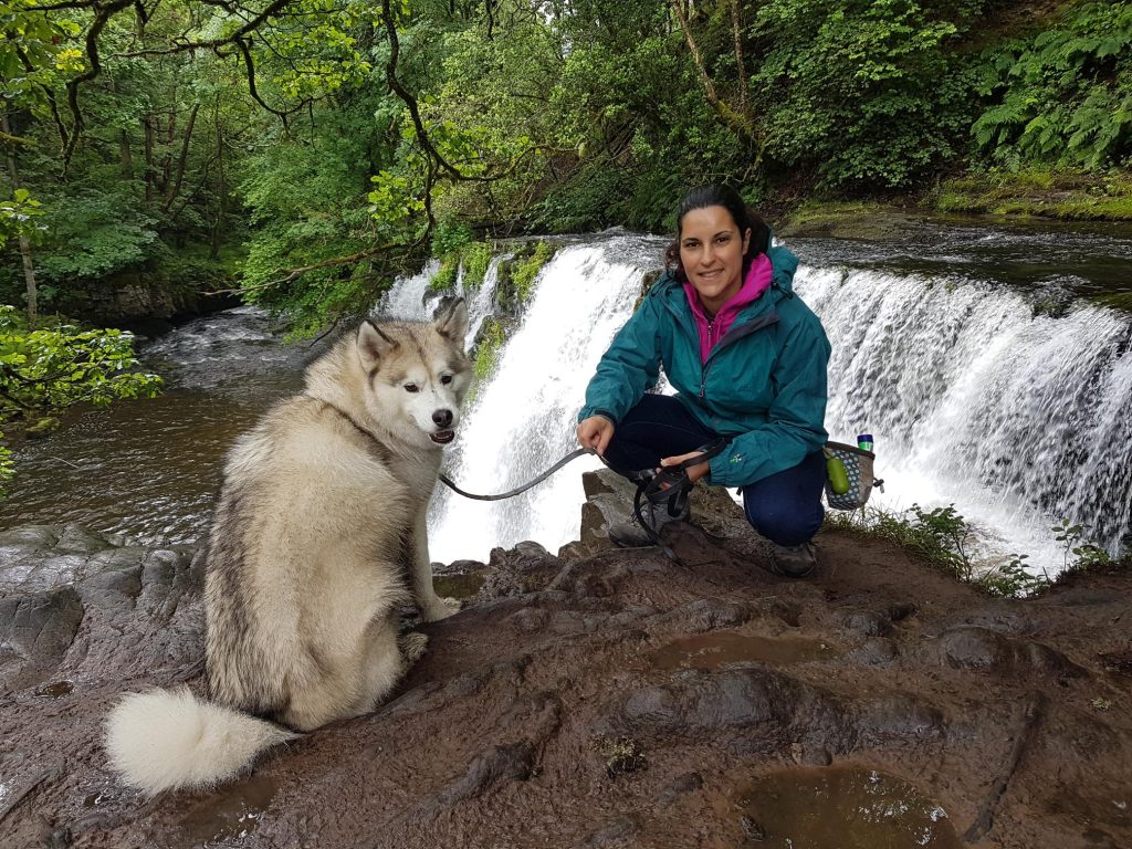 Haku, my rescue dog, and me in front of a waterfall in a forest